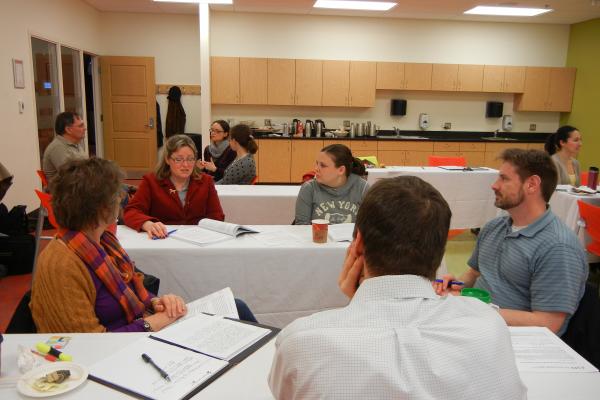 Five instructors discuss their teaching at tables during a WAC discussion event